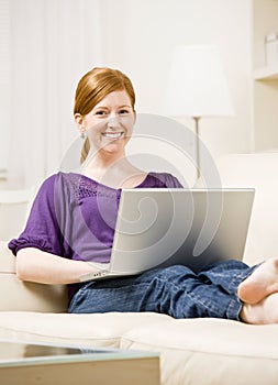 Woman relaxing on sofa typing on laptop