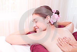 Woman relaxing while Spa Therapist is oil massaging her back