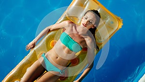 Woman relaxing and sun tanning by the swimming pool