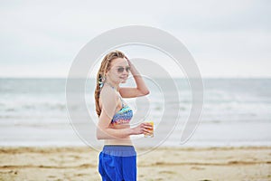 Woman relaxing and sunbathing on beach, drinking delicious fruit juice