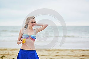Woman relaxing and sunbathing on beach, drinking delicious fruit juice