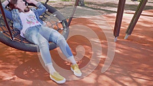 Woman is relaxing on swing on playgorund