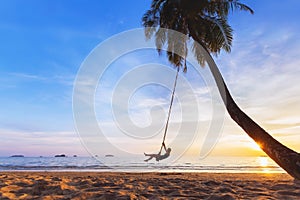 Woman relaxing on swing, tropical paradise beach at sunset, vacation