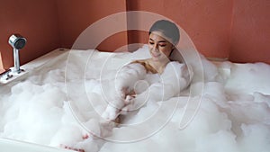 Woman relaxing and takes bubble bath in bathtub with foam