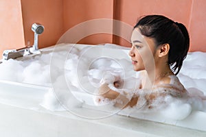 Woman relaxing and takes bubble bath in bathtub with foam