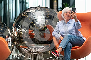 Woman relaxing in a tub chair in front of a modern sculpture