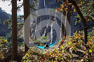 Woman relaxing in the turquoise hammock in a wood. Concept of relaxation and meditation