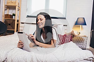 Woman relaxing and using digital tablet computer in the bed at home