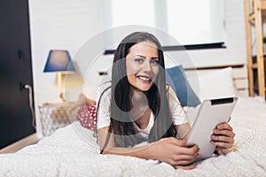 Woman relaxing and using digital tablet computer in the bed at home