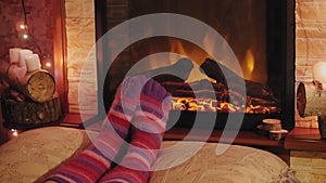 Woman relaxing by warm fire and warming up their feet