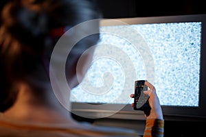 Woman with remote control in front of TV set