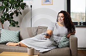 Woman with remote control and watching tv at home