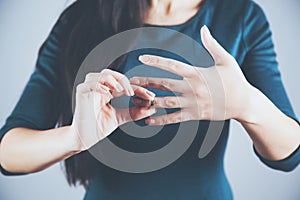 Woman remove ring on gray background.