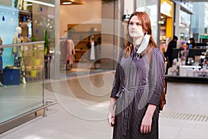 A woman in a removed medical mask in the shopping center. Redhead girl taked off mask after the end of the coronavirus epidemic photo