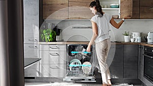 Woman removes clean ceramic dishes from dishwasher. Household and useful technology concept.