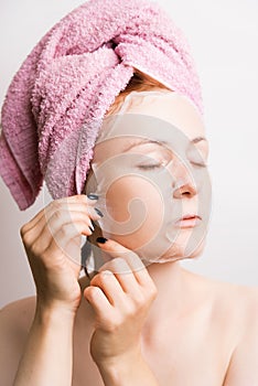 Woman removes cosmetic mask on face on light background