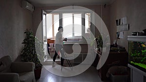 A woman removes potted flowers from a window and washes a window. A child is running next to her. Faster shooti