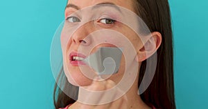 Woman removing adhesive tape from mouth