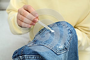 Woman removing chewing gum from jeans