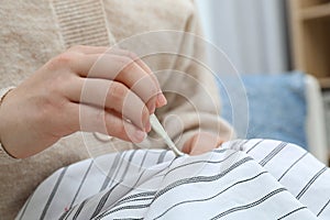 Woman removing chewing gum from shirt indoors, closeup