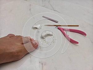 Woman removing cuticles from toes with pliers at home photo