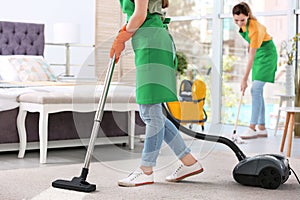 Woman removing dirt from carpet with vacuum cleaner