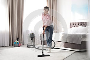 Woman removing dirt from carpet with vacuum cleaner