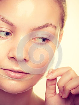 Woman removing facial peel off mask.