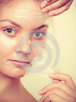 Woman removing facial peel off mask.