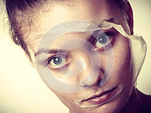 Woman removing facial peel off mask.