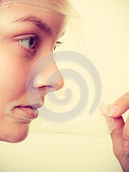 Woman removing facial peel off mask.