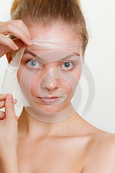 Woman removing facial peel off mask.