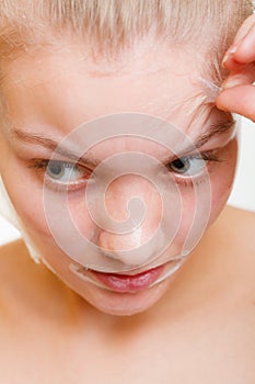 Woman removing facial peel off mask.