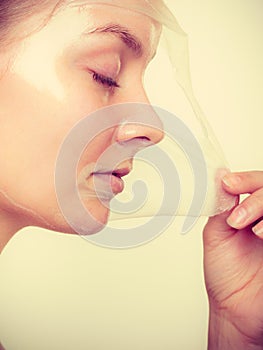 Woman removing facial peel off mask.