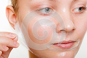 Woman removing facial peel off mask.