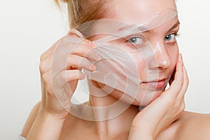 Woman removing facial peel off mask.