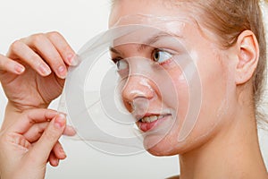 Woman removing facial peel off mask.