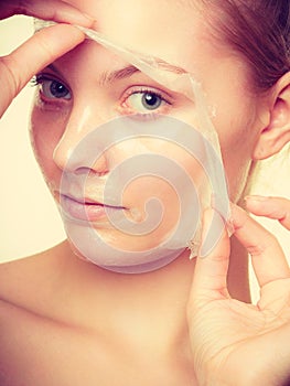 Woman removing facial peel off mask.