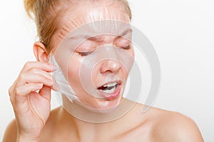 Woman removing facial peel off mask.