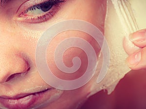 Woman removing facial peel off mask closeup