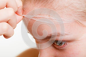 Woman removing facial peel off mask closeup