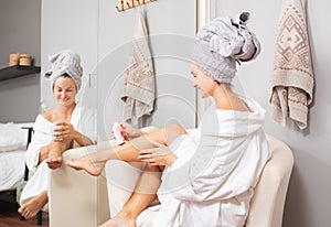 Woman is removing hair on her leg with an delectric epilator at home photo