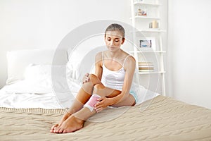 Woman removing leg hair with depilatory wax strip