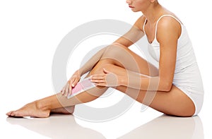 Woman removing leg hair with depilatory wax strip