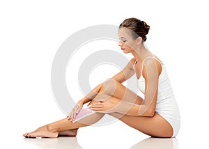 Woman removing leg hair with depilatory wax strip photo
