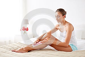 Woman removing leg hair with depilatory wax strip photo