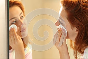 Woman removing makeup with a tissue in the bathroom