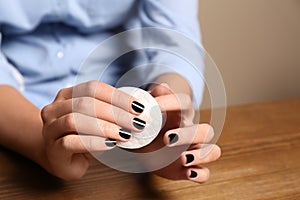 Woman removing nail polish at table, closeup