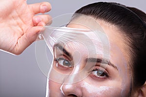 Woman Removing Peeling Mask From Her Face