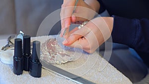 Woman removing shellac from nails using pusher and file, manicure at home.